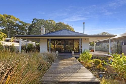 a house with a wooden walkway in front of it at Neptune in Raymond Island