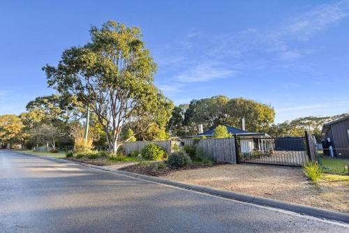 an empty street with a fence and a house at Neptune in Raymond Island