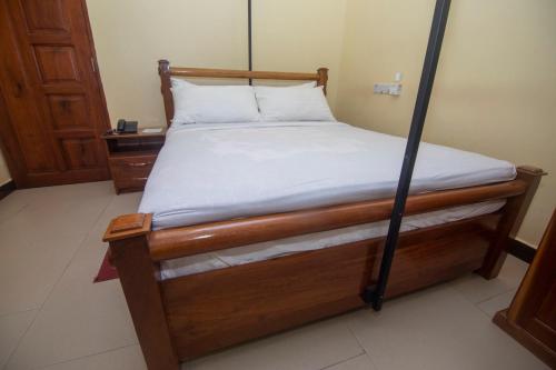 a bed in a room with a wooden bed frame at Randa Cottages Moshi in Kirua