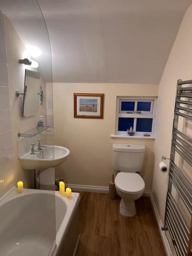 a bathroom with a tub and a toilet and a sink at Cottage K in Hinxton