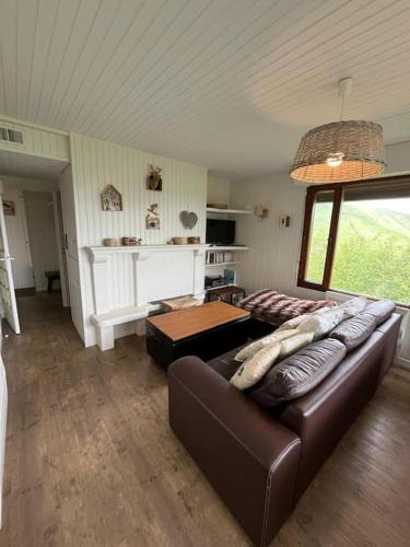 un salon avec un canapé en cuir et une table dans l'établissement Bel appart dans chalet Pla Adet, à Saint-Lary-Soulan