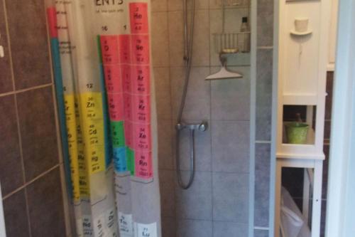 une douche avec des panneaux de différentes couleurs sur le mur dans l'établissement Longère en bois à 15 min de la mer, à Bretteville-Saint-Laurent