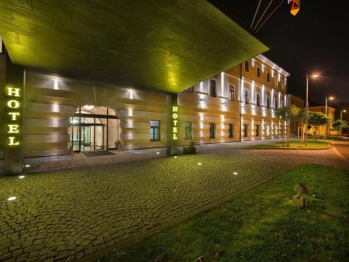 a building with a lit up sign in front of it at EA Hotel Tereziánský dvůr in Hradec Králové