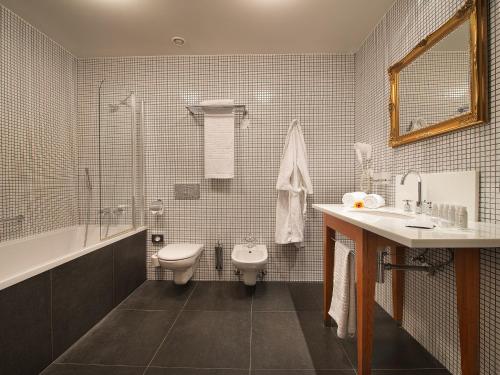 a bathroom with a sink and a toilet and a tub at EA Hotel Tereziánský dvůr in Hradec Králové