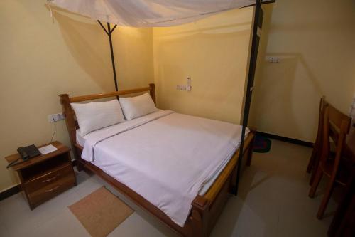 a bedroom with a canopy bed and a night stand at Randa Cottages Moshi in Kirua