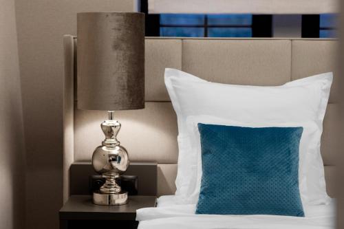 a bed with a blue pillow and a lamp on a table at Grand Park Hotel in Szczecin