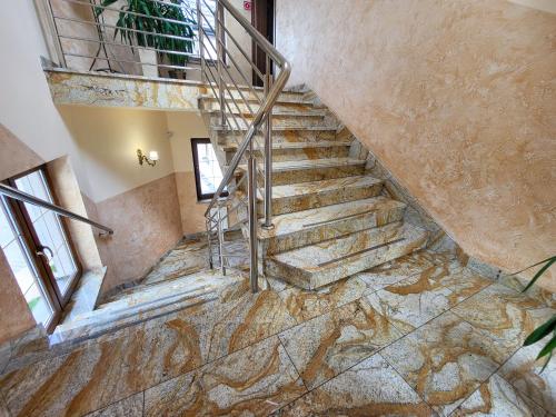 a staircase in a house with marble flooring and a stair railing at Hotel Hesperus in Międzyrzec Podlaski