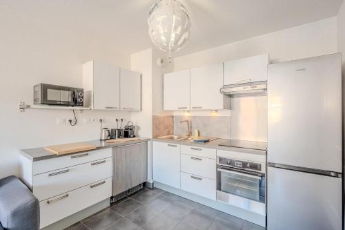 une cuisine avec des armoires blanches et des appareils en acier inoxydable dans l'établissement Le Neroli T2 dernier étage avec Terrasse et garage, à Toulon
