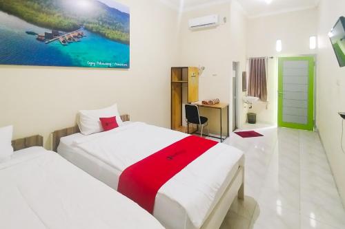 une chambre avec deux lits et un bureau dans l'établissement RedDoorz Syariah at Shakira Alesha Enggal, à Bandar Lampung
