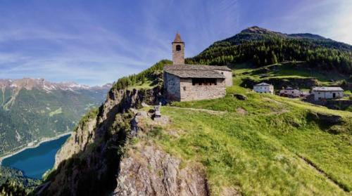 a building on top of a mountain with a body of water at casa Battilana Li Curt - Poschiavo in Prada