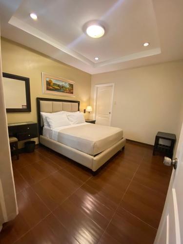a bedroom with a white bed and a wooden floor at Prism Hotel in Angeles