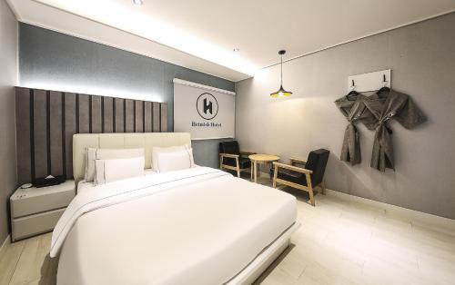 a bedroom with a large white bed and a table at Heimish Hotel in Tongyeong