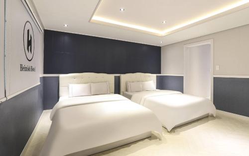 two beds in a room with white furniture at Heimish Hotel in Tongyeong