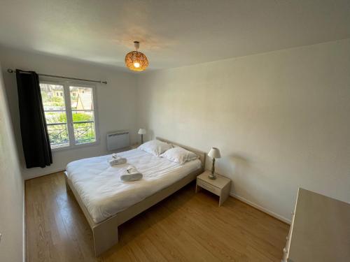 une chambre avec un lit blanc et une fenêtre dans l'établissement Maisonette proche plage, à Colleville-Montgomery