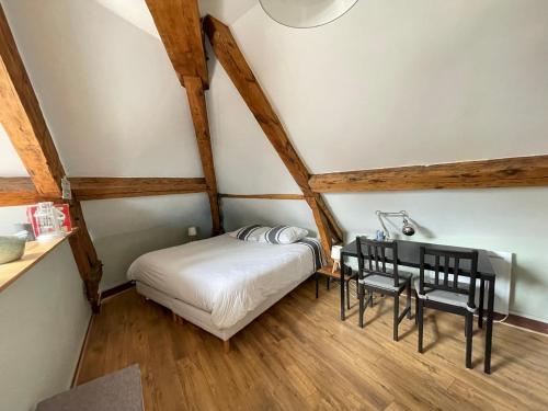 バイユーにあるLes combles de l Aure Grand studio cosy confortable classé 3 étoiles centre Bayeux 2 mn à pied cathédrale proche plages du débarquementのベッドとテーブルと椅子のある小さな部屋