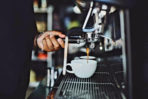 a person preparing a cup of coffee in a espresso machine at Heimish Hotel in Tongyeong