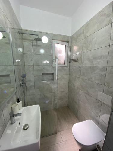 a bathroom with a toilet and a sink and a shower at Yard Paradise in Dhërmi