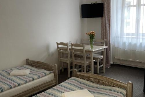a room with two beds and a table with a vase of flowers at Kolštejn wellness centrum in Branná