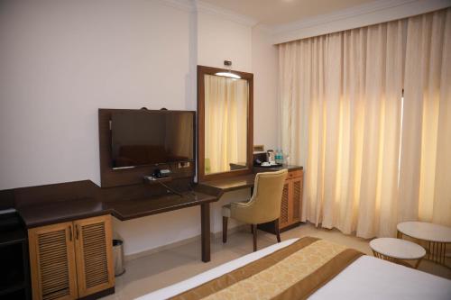 a hotel room with a bed and a desk with a television at The Ontime Hotel, Bangalore in Bengaluru