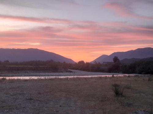 a sunset over a river with mountains in the background at Camping DRINO VALLEY in Gjirokastër