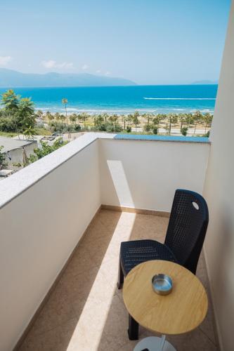a balcony with a table and a chair and the ocean at Voyage Villa in Vlorë