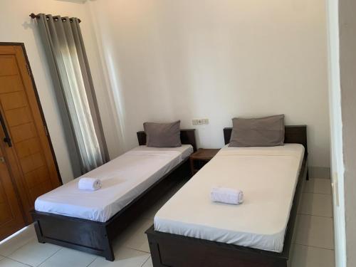 Dos camas en una habitación con sábanas blancas. en Bale sunrise, en Gili Trawangan