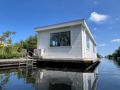 a house is sitting on a dock in the water at New- Private Cosy Houseboat, on a lake near Amsterdam in Vinkeveen