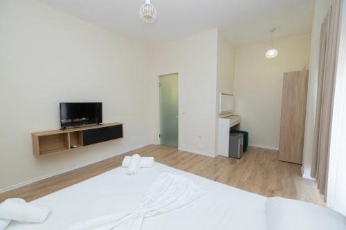 a white bedroom with a bed and a flat screen tv at Voyage Villa in Vlorë