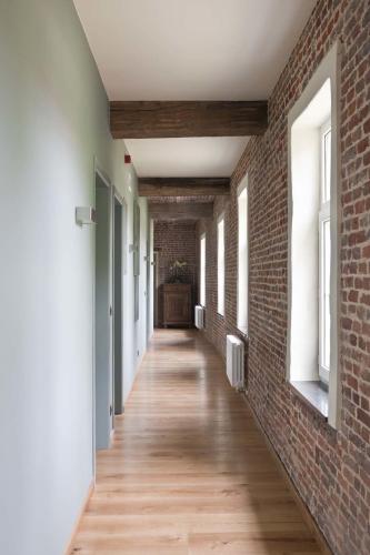 an empty hallway with a brick wall and wooden floors at Lozerkasteel in Kruishoutem