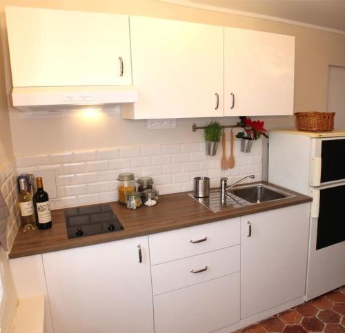 une cuisine avec des armoires blanches et un évier dans l'établissement Agréable studio à 1 min du Château de Versailles, à Versailles