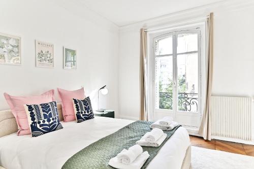 une chambre blanche avec des oreillers roses et bleus et un lit dans l'établissement Appartement parisien spacieux #Marais #Rivoli, à Paris