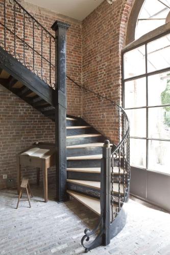 a staircase in a brick building with a bench and a table at Lozerkasteel in Kruishoutem