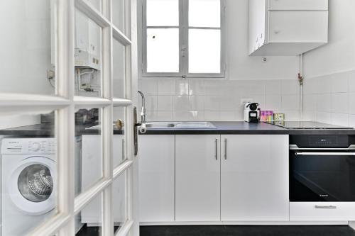 une cuisine blanche avec un évier et une machine à laver dans l'établissement Appartement parisien spacieux #Marais #Rivoli, à Paris