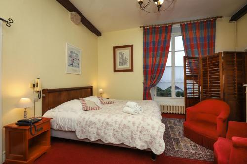 a bedroom with a bed and a red chair at Logis Cote Loire - Auberge Ligerienne in Blois