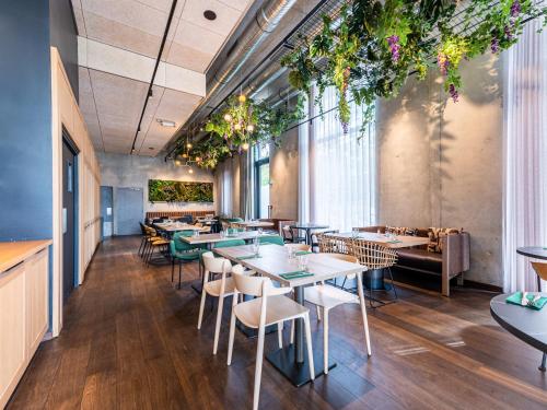 a restaurant with tables and chairs and plants at Novotel Annemasse Centre - Porte de Genève in Annemasse