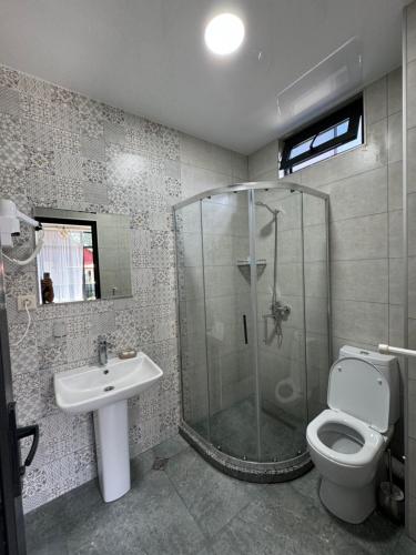 a bathroom with a shower and a toilet and a sink at Best House in K'obulet'i