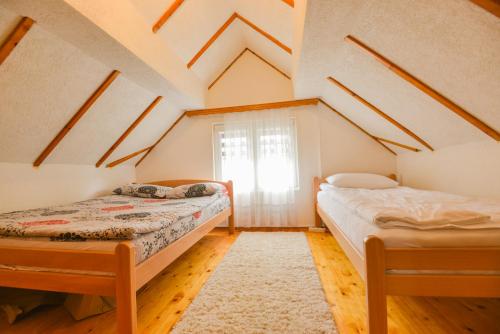 2 Betten in einem Dachzimmer mit Fenster in der Unterkunft Villa Miris Prirode Zenik in Ilidža