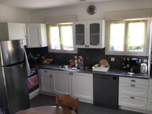 une cuisine avec des armoires blanches et un réfrigérateur en acier inoxydable dans l'établissement Le chêne vert, à Saint Alban Auriolles