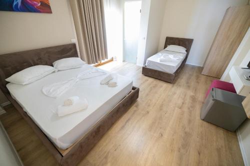 a bedroom with two beds with white sheets and wooden floors at Voyage Villa in Vlorë