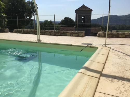 un bassin d'eau avec une tour d'horloge en arrière-plan dans l'établissement Le chêne vert, à Saint Alban Auriolles