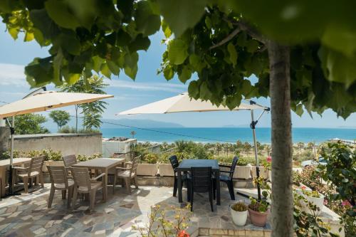 a patio with tables and chairs and an umbrella at Voyage Villa in Vlorë