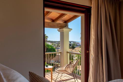 a room with a door open to a balcony with chairs at MalaQuita Hotel Boutique in Santa Eularia des Riu