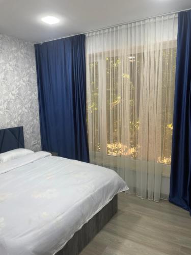 a bedroom with a large bed and blue curtains at Dream home in Vanadzor