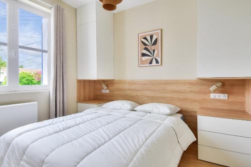a white bedroom with a large bed and a window at Coup de coeur - 200m plage - 6 adultes - 4 enfants in Le Grand Vieil
