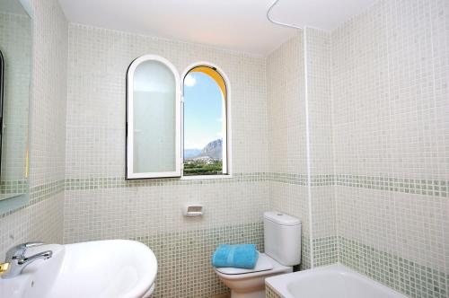 a bathroom with a toilet and a sink and a window at Apartamento Belvedere - Deniasol in Denia