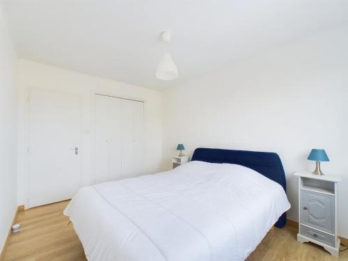 a bedroom with a white bed and a night stand at Appart pour 4 centre ville - proche de la gare in Saint-Hilaire-de-Riez