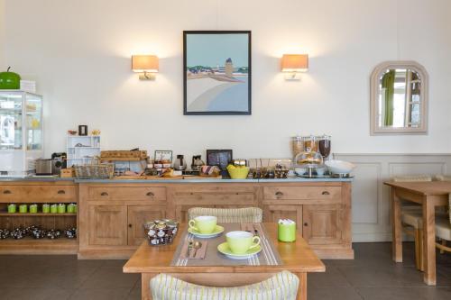 une cuisine avec des placards en bois et une table avec des chaises dans l'établissement Hotel Ajoncs d'Or, à Saint-Malo