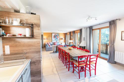 une cuisine et une salle à manger avec une table et des chaises rouges dans l'établissement Chalet Galbert, Vaujany, à Vaujany