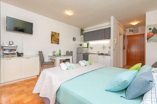 a bedroom with a large blue bed and a kitchen at Jasna - apartman studio in Pula