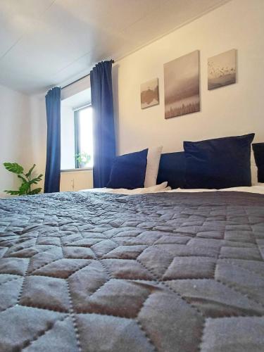 a bedroom with a bed with blue curtains and a window at Central Large Double Room With Free Parking in Hjørring